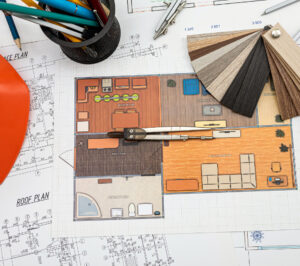 Particolare di una mappa di un progetto di casa con sopra matite, casco da cantiere e mazzetta finiture
